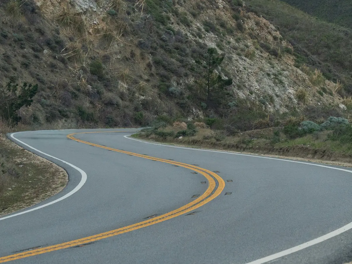 Car, traffic cones and a road sign removed from a winding coastal road